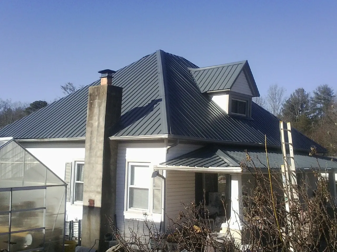 Dark blue standing seam metal roof on a white farmhouse with dormer — Slate & Tile Roof Repair by Roofing Brothers in Cathlamet