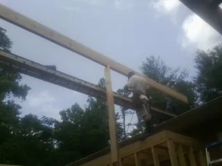 Carpenter setting a ridge beam over a new addition frame — Ice Dam Removal by Roofing Brothers in Cathlamet