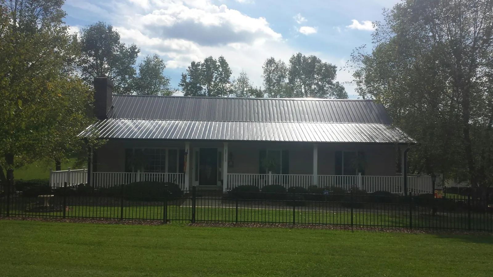 Gray metal roof on a brick ranch with a full width front porch — Gutter Guard Installation work by our crew in Cathlamet