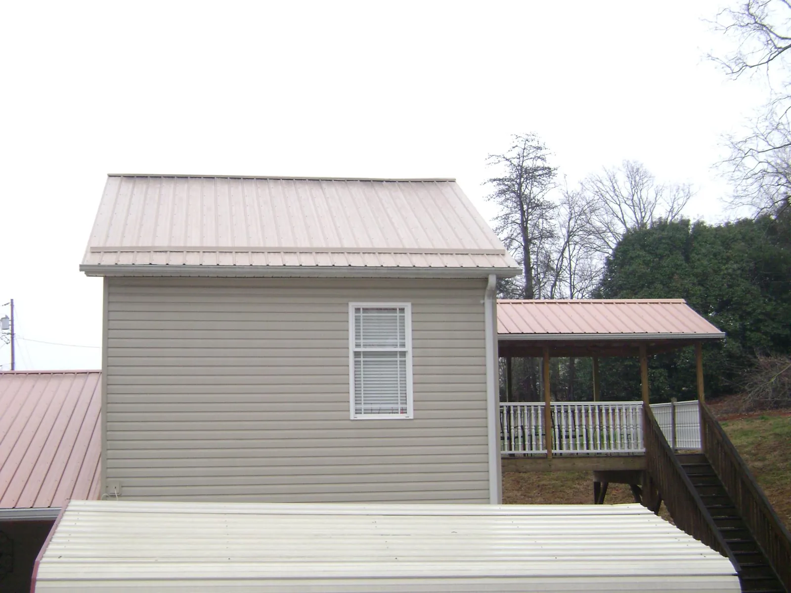 Tan metal roofs on a two story addition and attached porch, from a Roof Replacement job in Cathlamet
