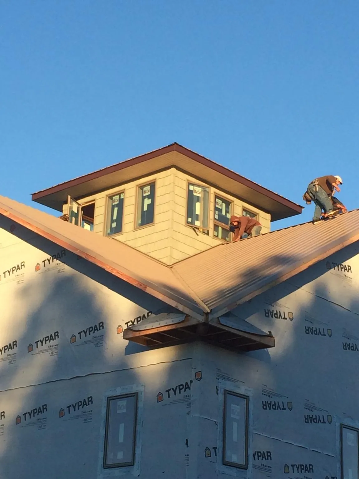 Roofers working around a rooftop cupola on a new metal roof at sunset — Roof Waterproofing in Cathlamet by Roofing Brothers